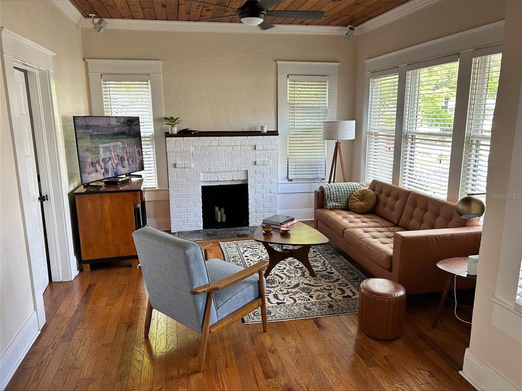 A living room features a white brick fireplace, wood flooring, and a wood-paneled ceiling — 4922 N SUWANEE AVENUE, TAMPA, FL