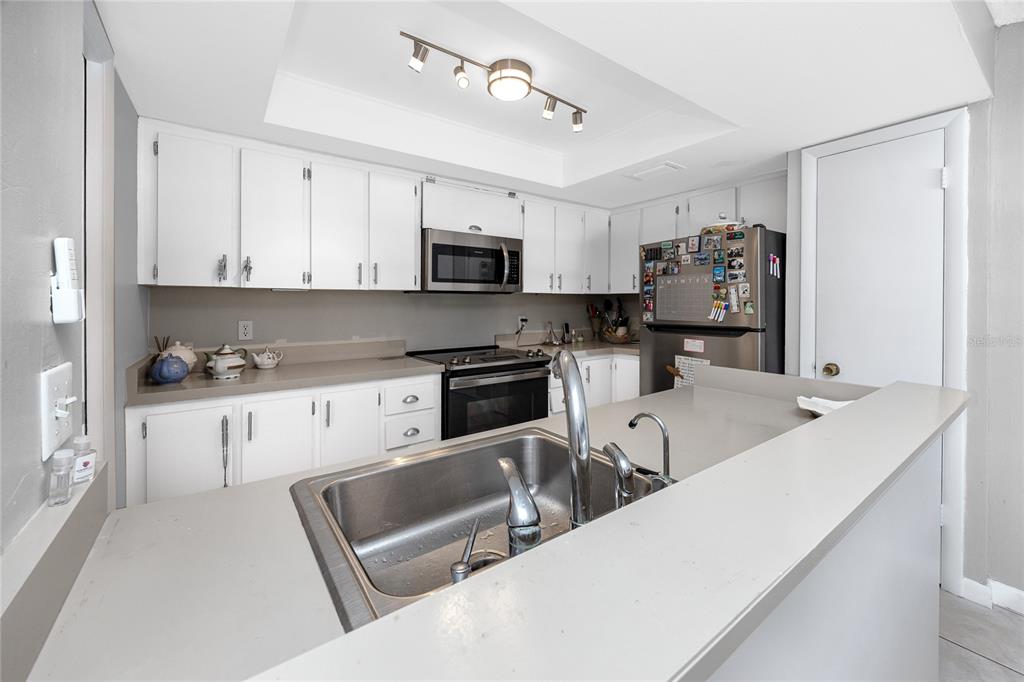 A kitchen with white cabinets, stainless steel appliances, and a peninsula sink — 2621 COVE CAY DRIVE UNIT 309, CLEARWATER, FL