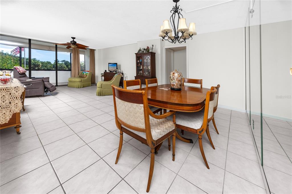 A dining area with a wooden table and chairs sits in an open-concept room with tile floors — 2621 COVE CAY DRIVE UNIT 309, CLEARWATER, FL