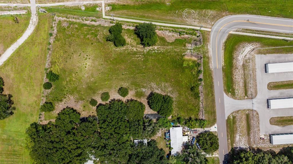 An aerial view shows a rectangular vacant lot bordered by a road and trees — NE 13TH LANE, OKEECHOBEE, FL