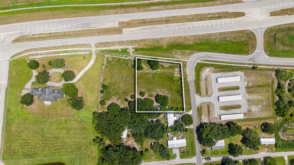 An aerial view shows a rectangular vacant lot outlined in white near a highway — NE 13TH LANE, OKEECHOBEE, FL