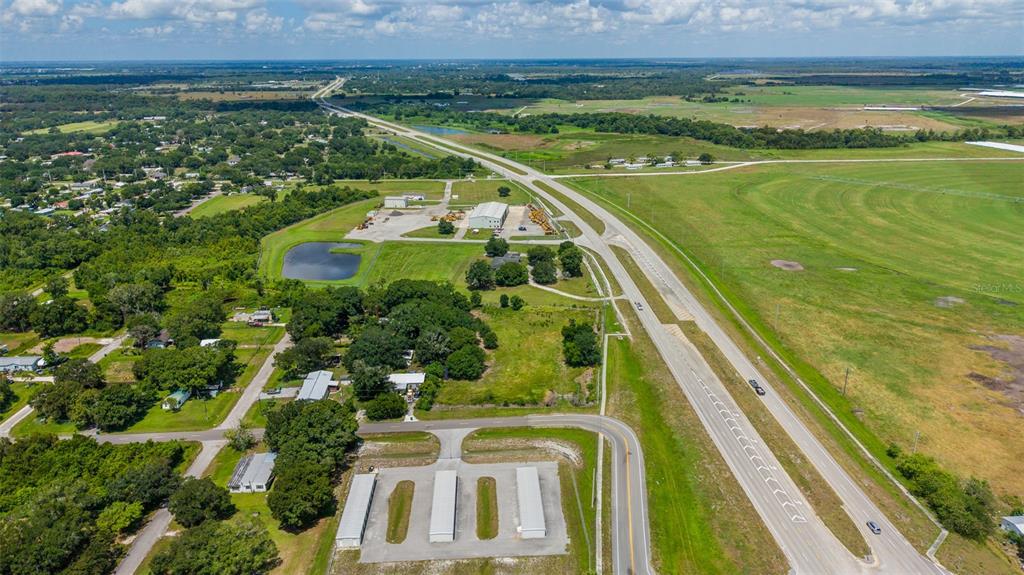 An aerial view shows a commercial property with storage units, a warehouse, and nearby highway — NE 13TH LANE, OKEECHOBEE, FL