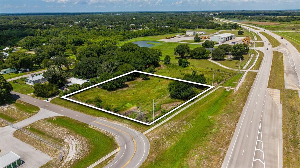 An aerial view shows a vacant, rectangular lot outlined in white next to a road — NE 13TH LANE, OKEECHOBEE, FL