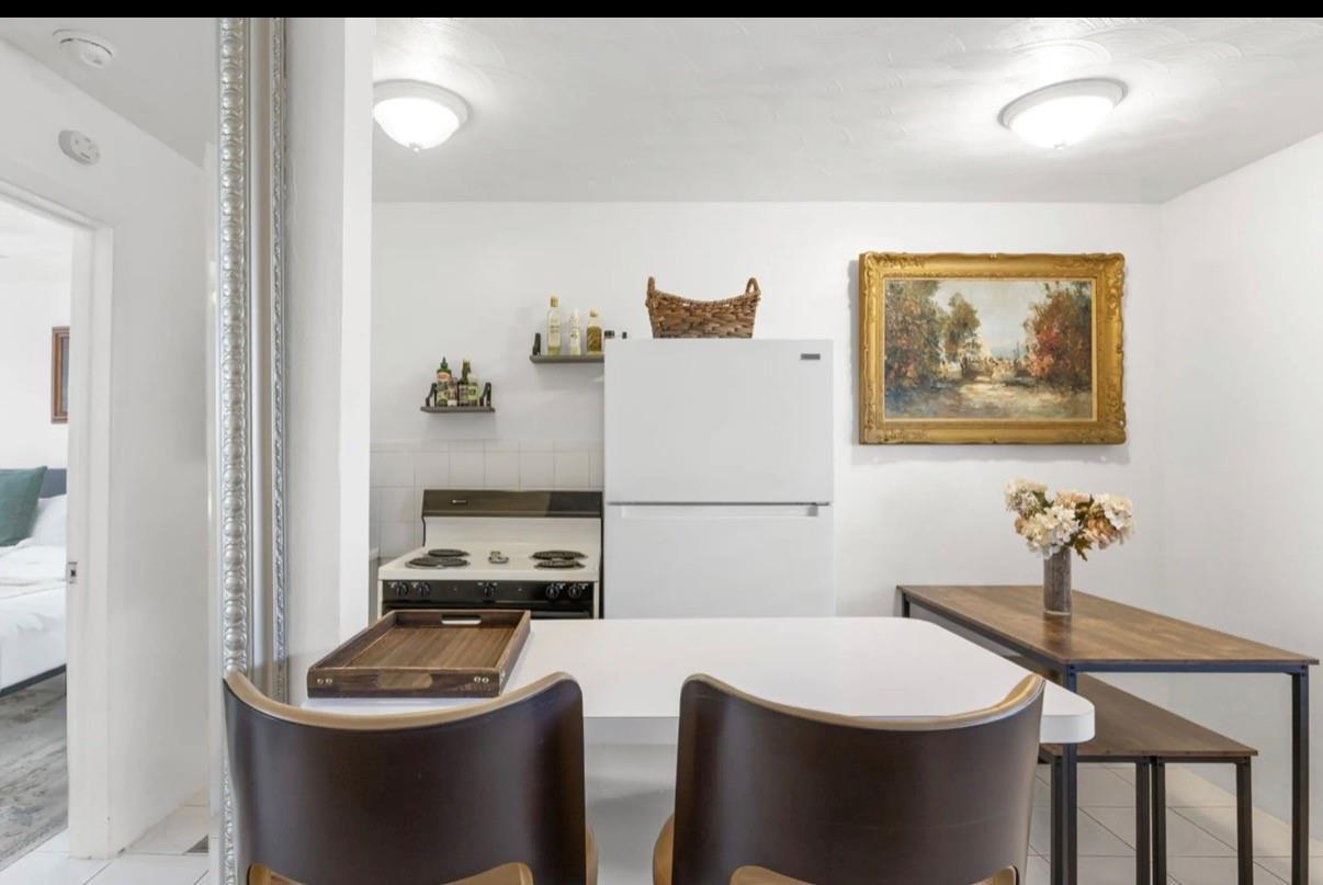 A kitchen features a white refrigerator, a stove, a dining table, and two chairs — 820 NE 16th Avenue # 3, Fort Lauderdale FL 33304, FORT LAUDERDALE, FL