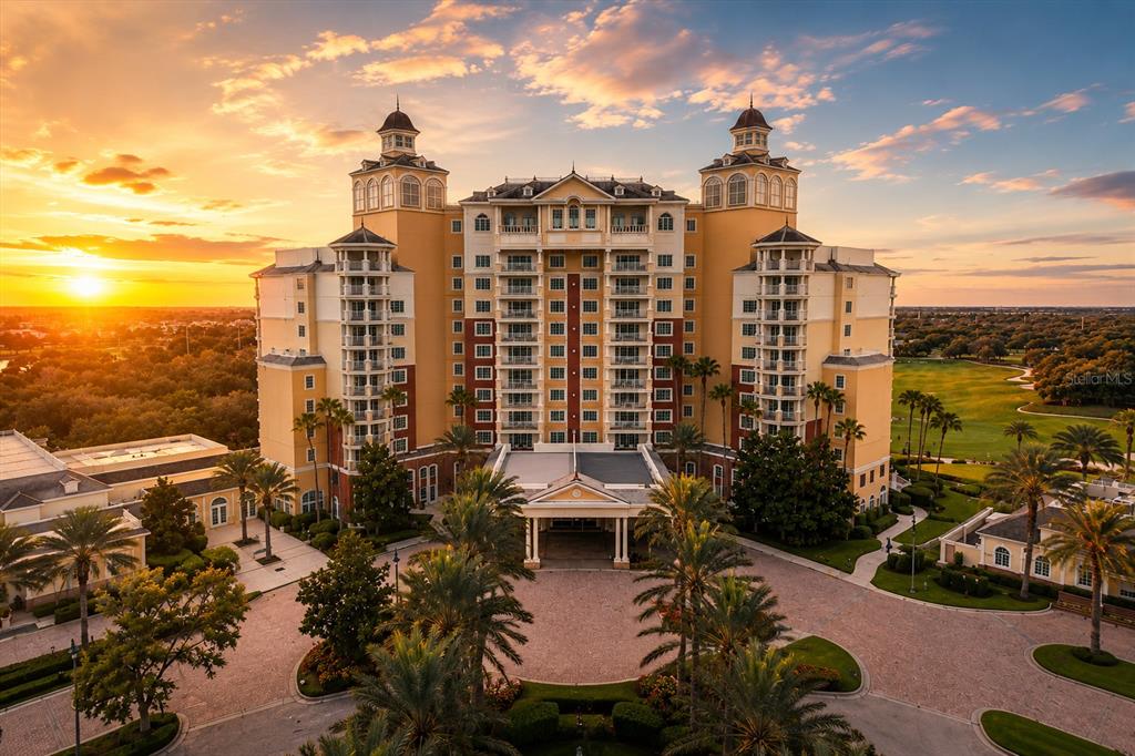 An aerial view of a large, multi-story hotel building with a circular driveway at sunset — 341 MUIRFIELD LOOP, KISSIMMEE, FL