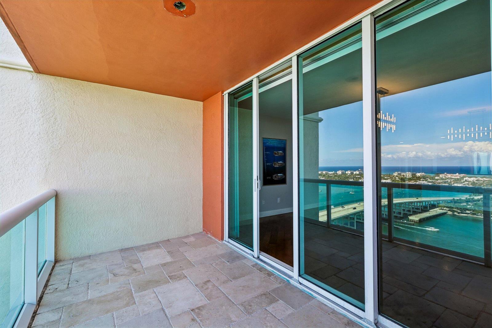 A balcony with stone tile flooring, a glass railing, and sliding doors overlooking the ocean — 2640 Lake Shore Drive # 2508, Riviera Beach FL 33404, RIVIERA BEACH, FL