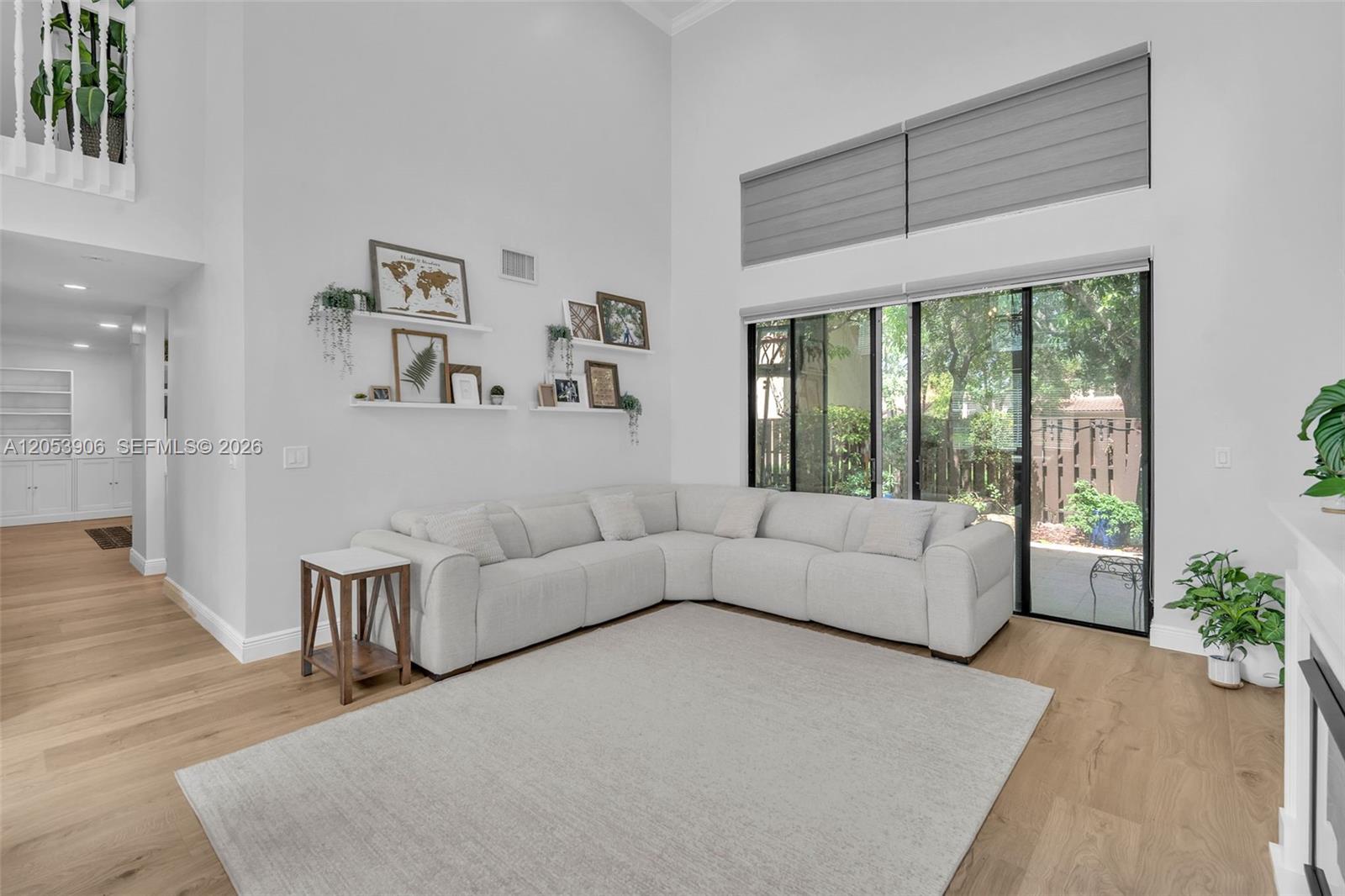 A living room features a white sectional sofa, light wood floors, and floor-to-ceiling windows — 1651 NW 104th Ave, Plantation FL 33322, PLANTATION, FL