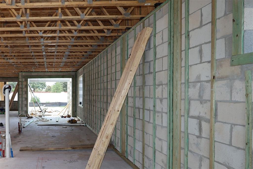 An interior view of a house under construction featuring concrete block walls and wooden trusses — 17043 OVERSTORY ROAD, ORLANDO, FL