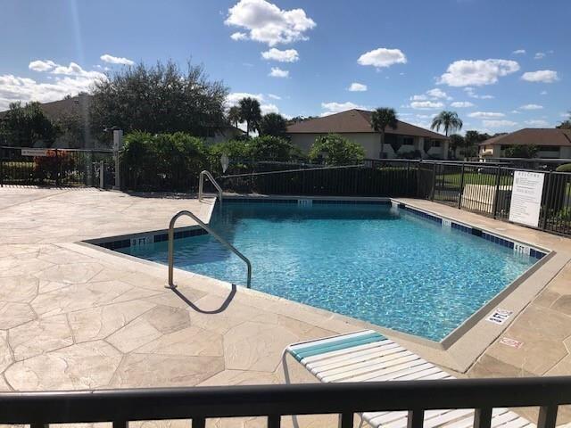 A rectangular swimming pool with a metal handrail sits on a paved patio with lounge chairs — 6303 SE Williamsburg Drive # 201, Hobe Sound FL 33455, HOBE SOUND, FL