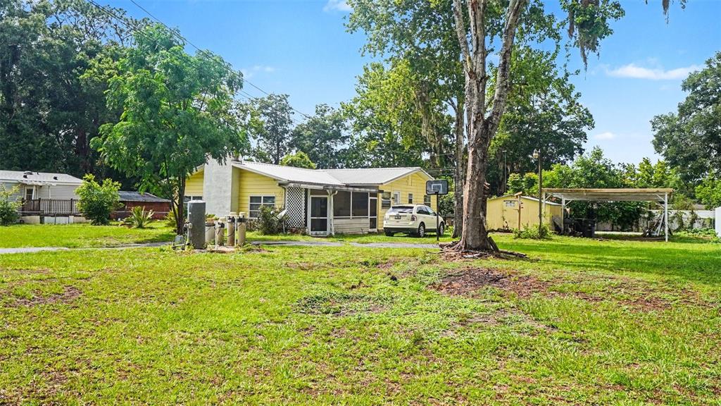A yellow single-story house with a metal roof sits on a large grassy lot — 4997 SE 145TH PLACE, SUMMERFIELD, FL