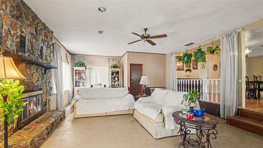 A living room features a stone fireplace, two white sofas, and a ceiling fan — 4997 SE 145TH PLACE, SUMMERFIELD, FL