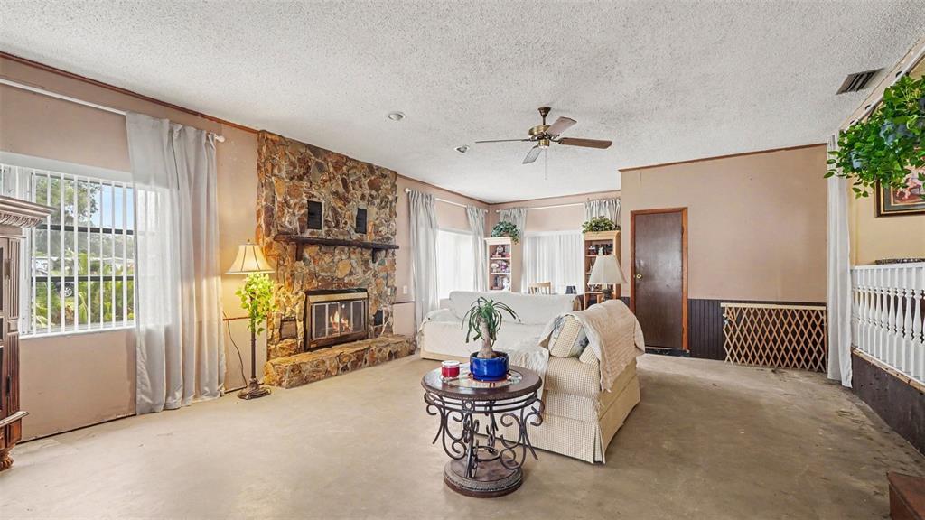 A living room features a stone fireplace, a ceiling fan, and a light-colored sofa — 4997 SE 145TH PLACE, SUMMERFIELD, FL