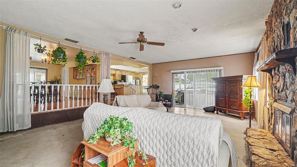 A living room features a stone fireplace, a ceiling fan, and a raised dining area — 4997 SE 145TH PLACE, SUMMERFIELD, FL