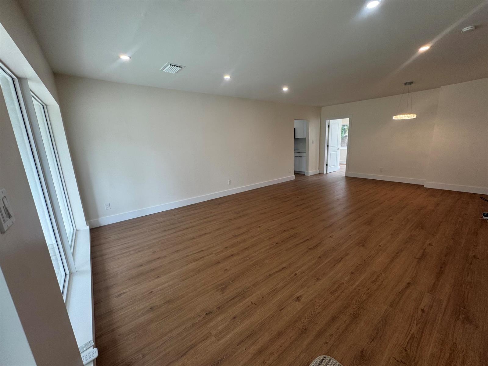 An empty room features light-colored walls, recessed lighting, and wood-look flooring — 725 NE 160th Terrace, Miami FL 33162, MIAMI, FL