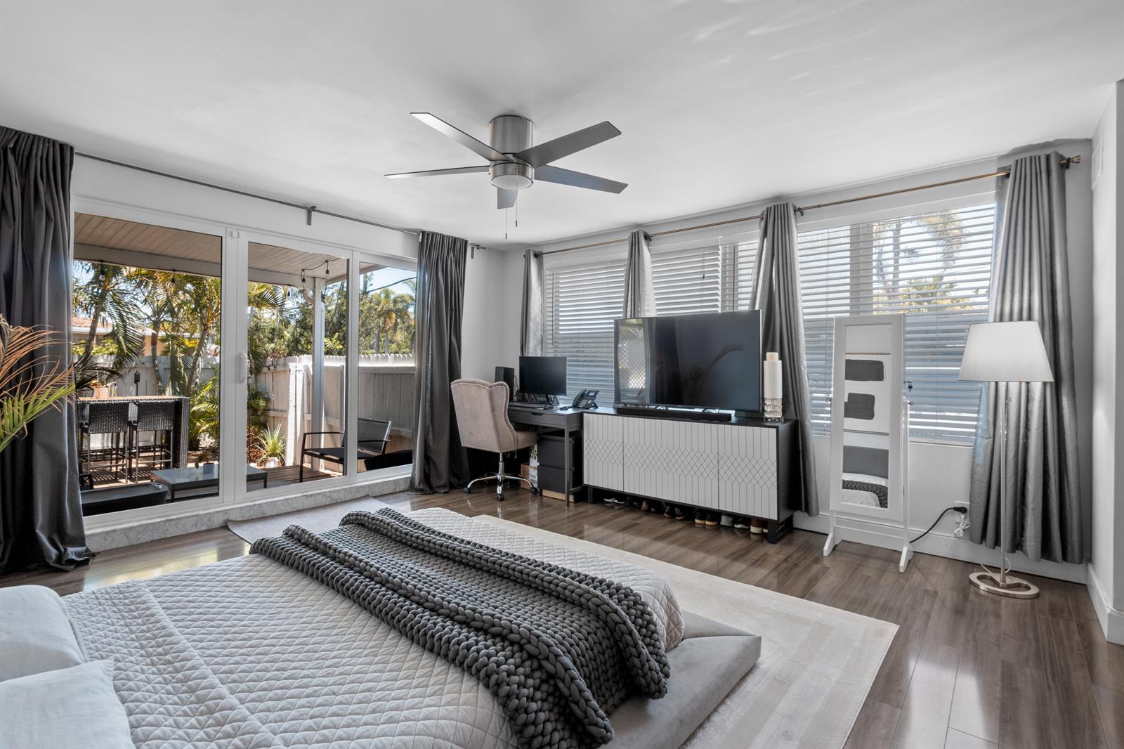 A bedroom with a bed, desk, television, and sliding glass doors leading to a patio — 1603 Jefferson Street, Hollywood FL 33020, HOLLYWOOD, FL