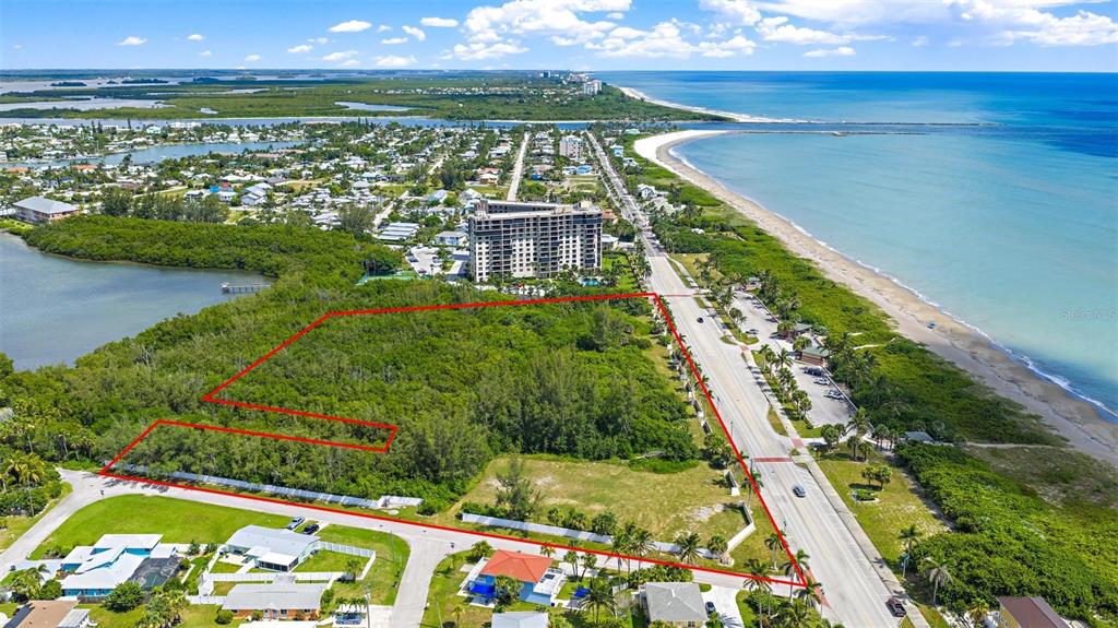 An aerial view shows a vacant, tree-covered lot outlined in red next to a coastal road — 901 S OCEAN DRIVE, FORT PIERCE, FL