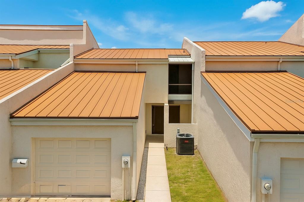 An exterior view of a townhouse with a metal roof, garage, and a small walkway — 4360 OUTRIGGER LANE, TAMPA, FL