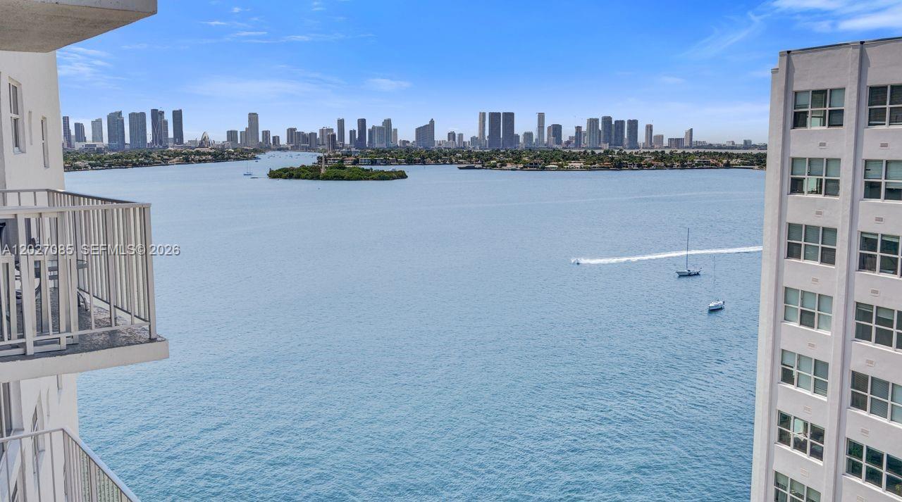 A high-rise balcony overlooks a wide bay with a distant city skyline — 1228 West Ave # 1404, Miami Beach FL 33139, MIAMI BEACH, FL