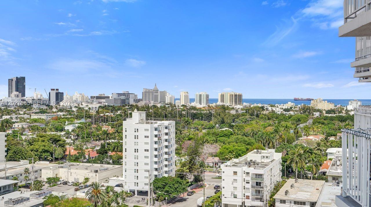 An elevated view of a city skyline, lush green trees, and the ocean in the distance — 1228 West Ave # 1404, Miami Beach FL 33139, MIAMI BEACH, FL