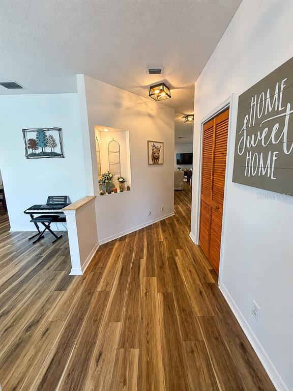 A hallway with wood-look flooring, a recessed wall niche, and a wooden louvered closet door — 859 HARBOR HILL DRIVE, SAFETY HARBOR, FL