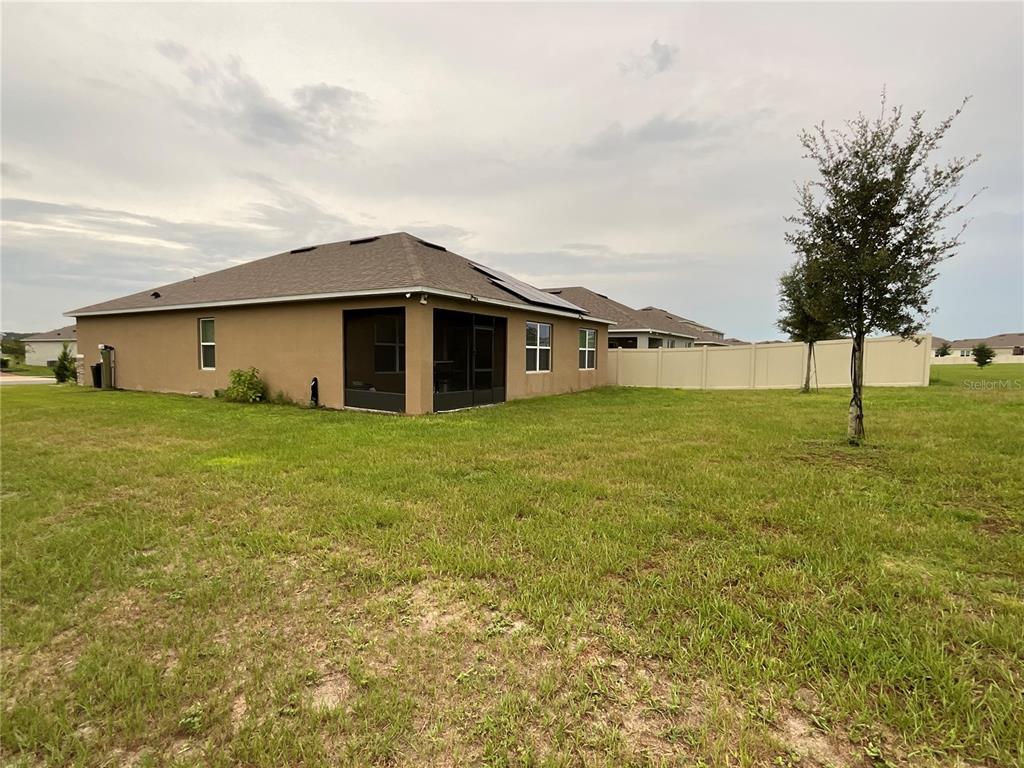 The exterior of a tan house with a screened-in patio and a fenced backyard — 33525 ALWAYS DREAMING COURT, SORRENTO, FL