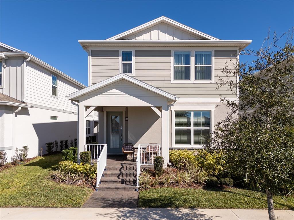 A two-story house with beige siding, a covered front porch, and a paved walkway — 14025 KAUAI DRIVE, ORLANDO, FL