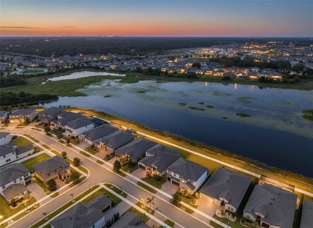 An aerial view of a suburban neighborhood at dusk featuring houses bordering a large lake — 12835 SATIN LILY DRIVE, RIVERVIEW, FL