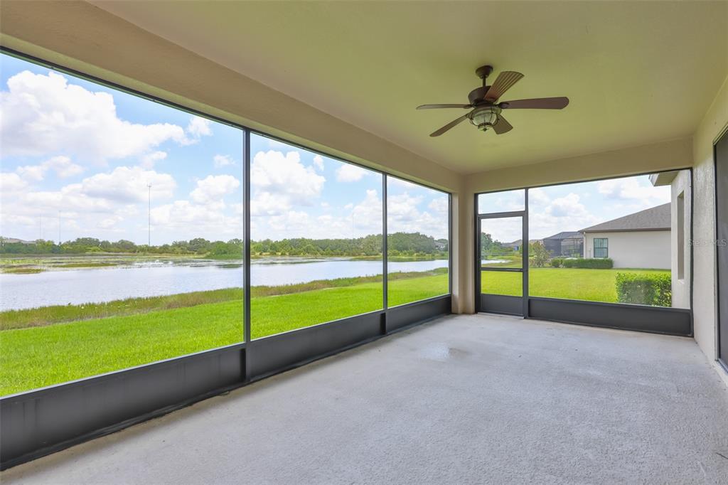 A screened-in patio with a ceiling fan overlooks a grassy lawn and a pond — 12835 SATIN LILY DRIVE, RIVERVIEW, FL