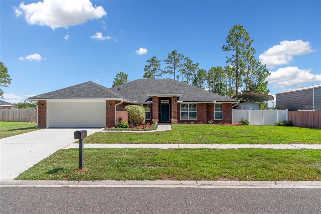 A single-story brick house with a two-car garage and a white vinyl fence — 4415 TALL PINES LANE, MIDDLEBURG, FL
