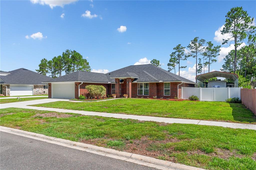 A single-story brick house with a dark shingled roof and an attached RV carport — 4415 TALL PINES LANE, MIDDLEBURG, FL