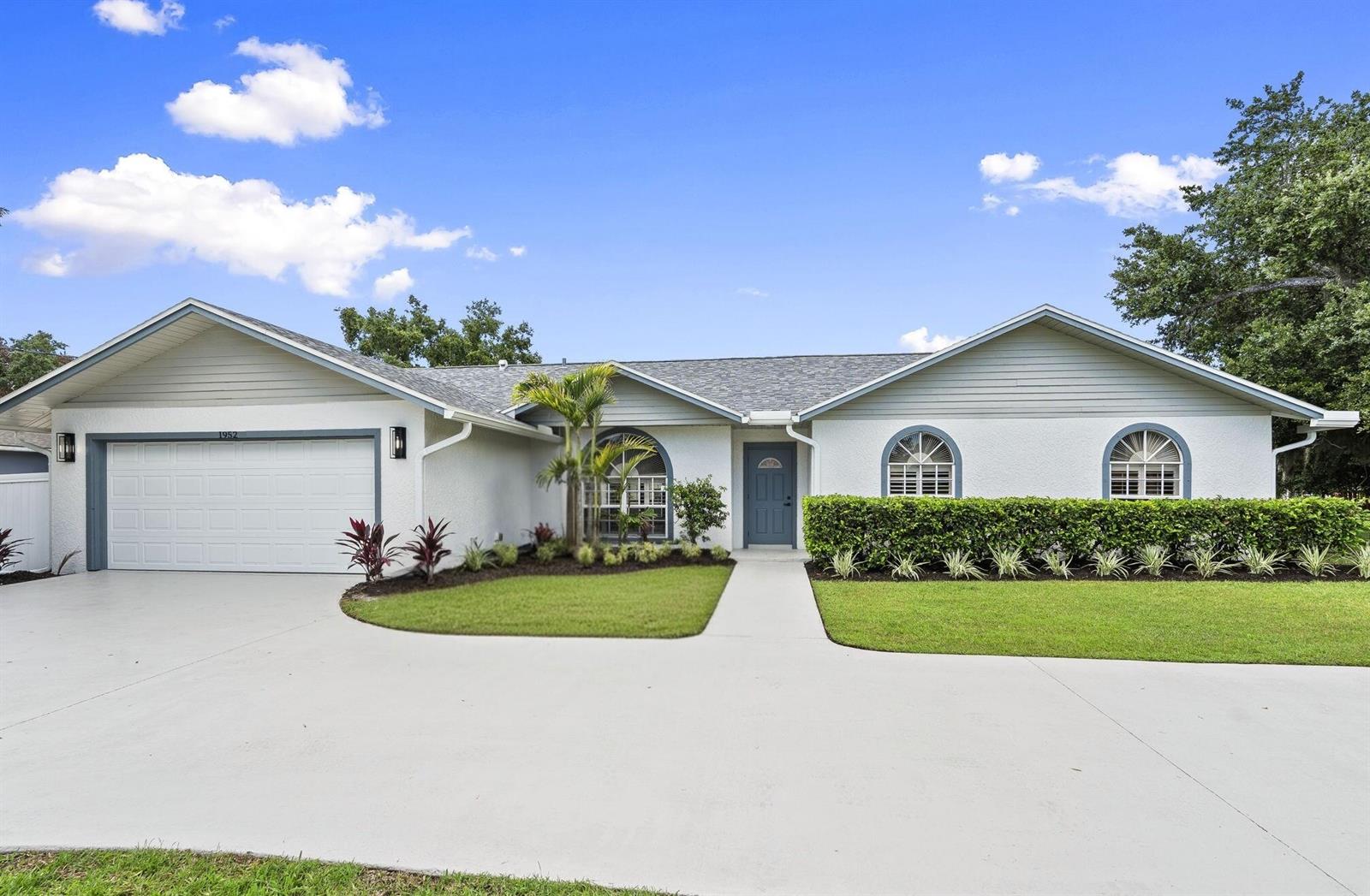 A single-story house with a white stucco exterior, gray trim, and a two-car garage — 1952 SW Import Drive, Port St. Lucie FL 34953, PORT ST. LUCIE, FL