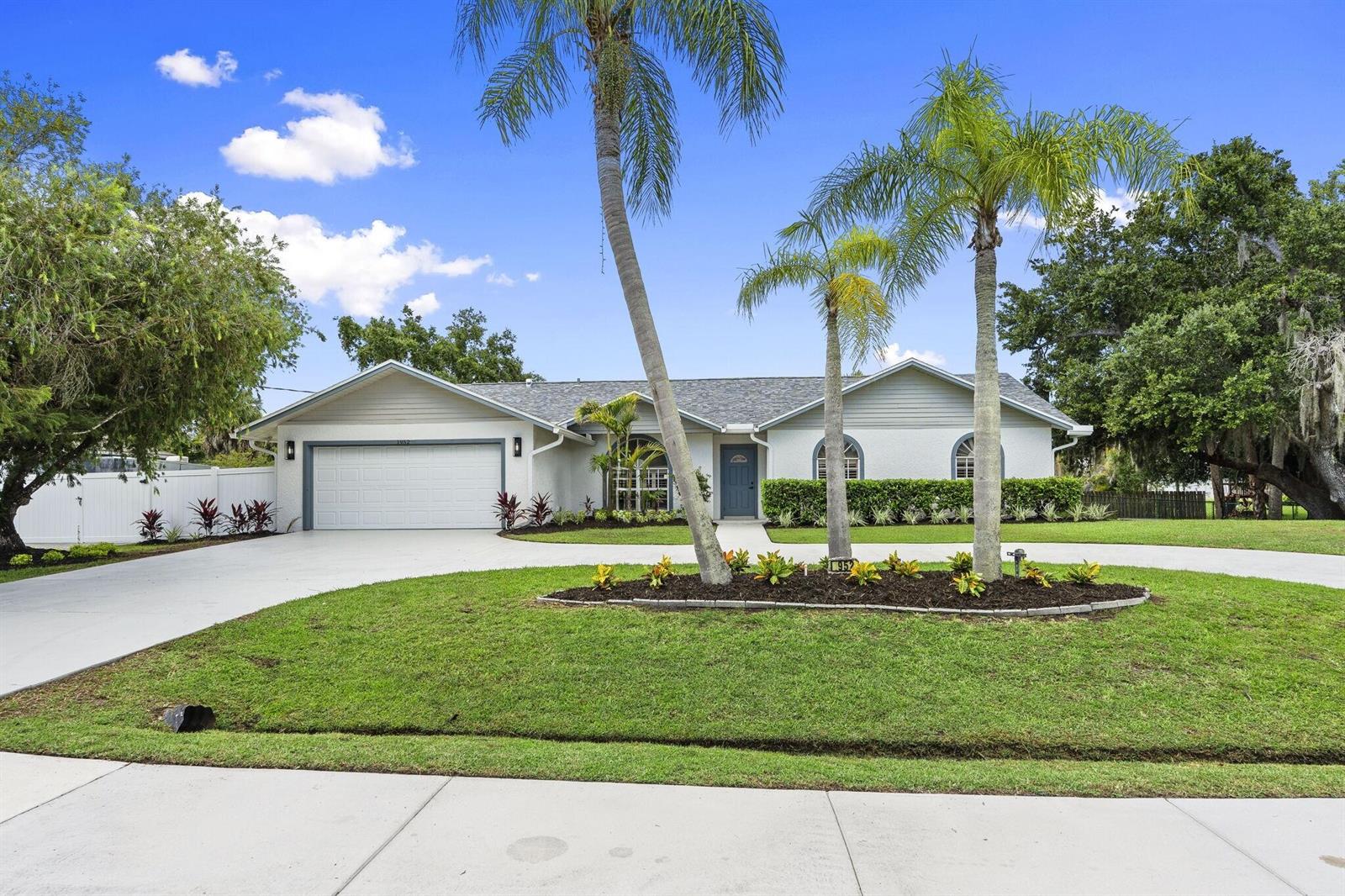 A single-story house with a white exterior, a two-car garage, and three palm trees — 1952 SW Import Drive, Port St. Lucie FL 34953, PORT ST. LUCIE, FL