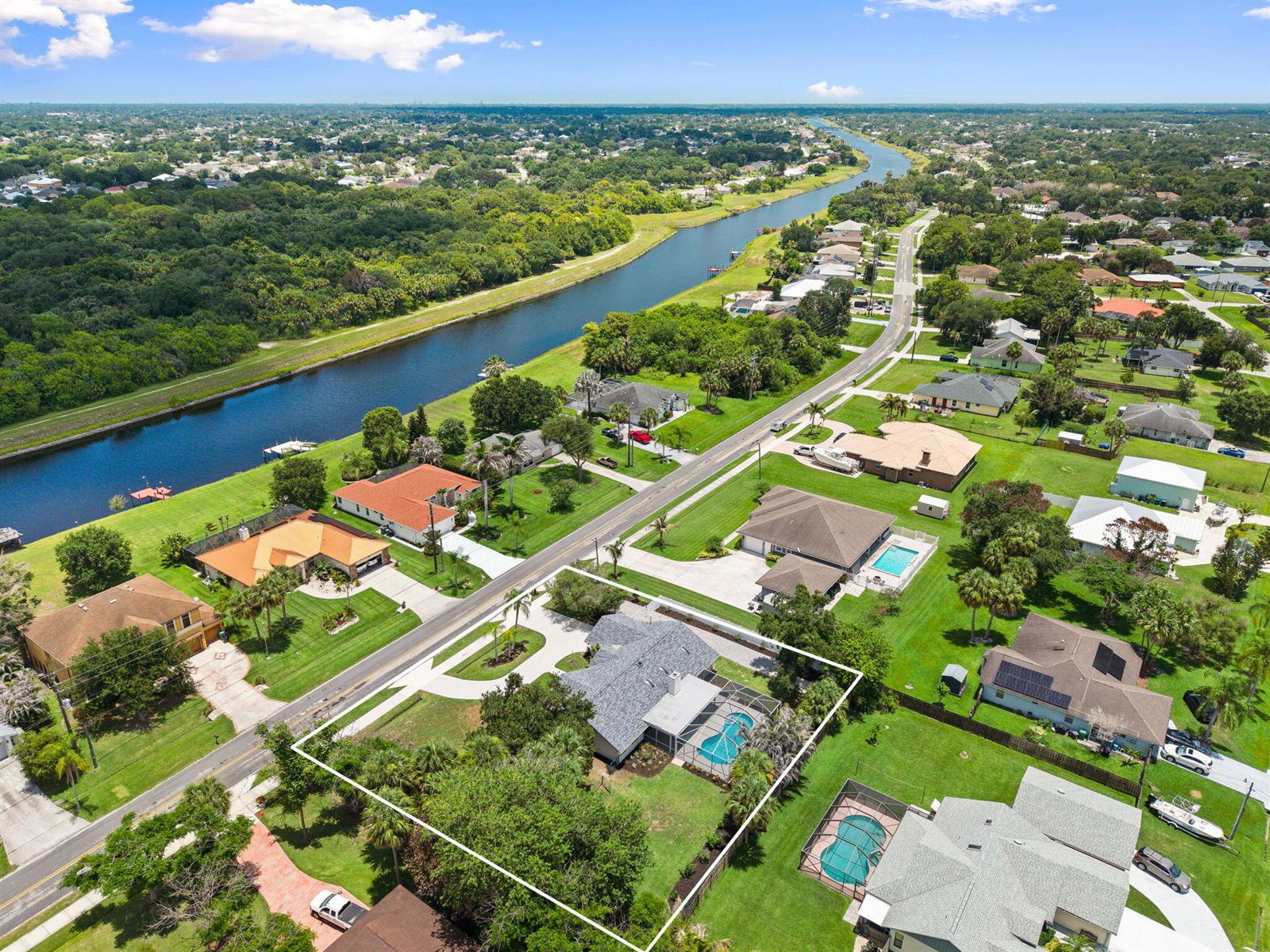 An aerial view shows a residential house with a pool and screened lanai — 1952 SW Import Drive, Port St. Lucie FL 34953, PORT ST. LUCIE, FL