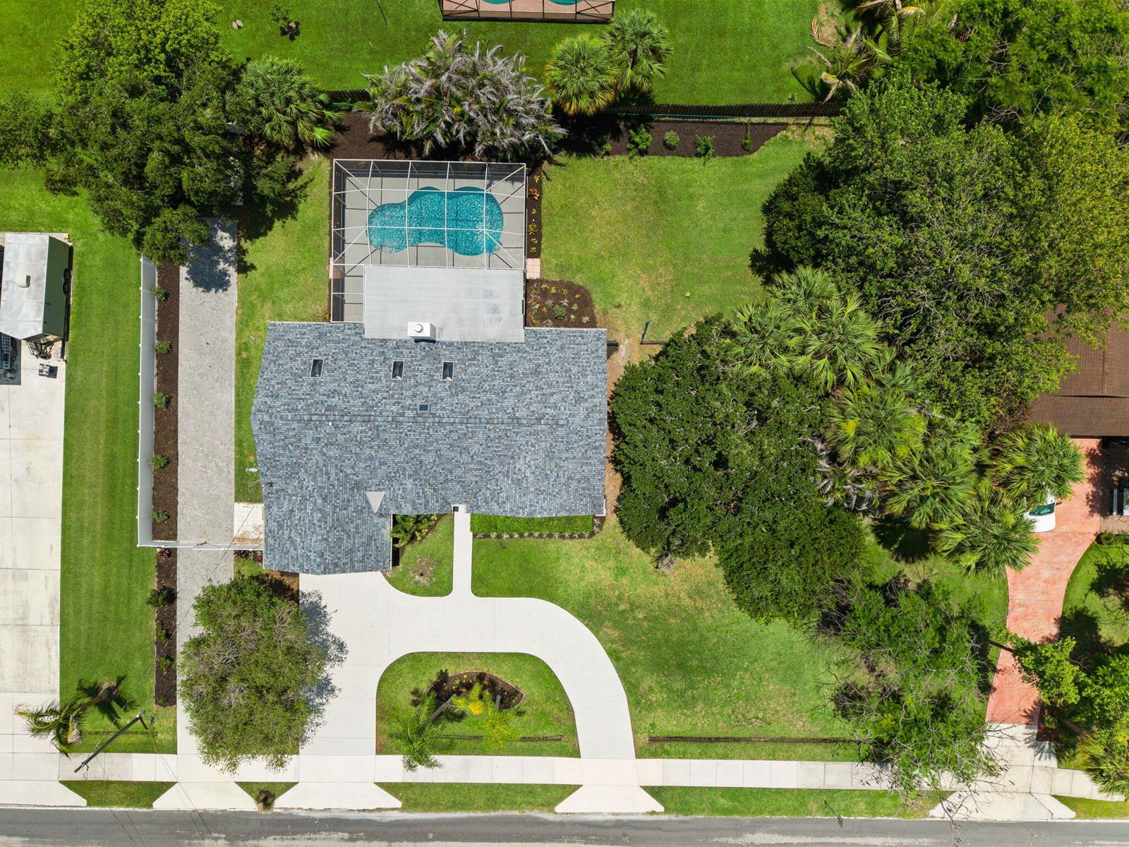 An aerial view shows a house with a pool, a circular driveway, and mature trees — 1952 SW Import Drive, Port St. Lucie FL 34953, PORT ST. LUCIE, FL