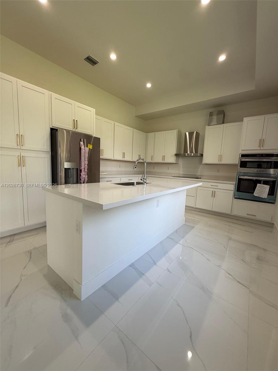 A modern kitchen features white cabinetry, a central island, stainless steel appliances, and tiled flooring — 9630 SW 208th Ter, Cutler Bay FL 33189, CUTLER BAY, FL