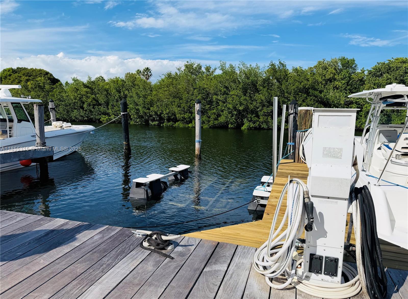 A wooden dock features a boat lift and utility pedestal alongside two moored motorboats — 6200 SW 152nd St #5, Palmetto Bay FL 33157, PALMETTO BAY, FL
