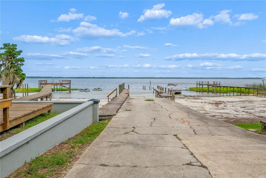 A concrete boat ramp leads to a lake with wooden docks on both sides — 21116 NE 101ST AVENUE UNIT 10, EARLETON, FL