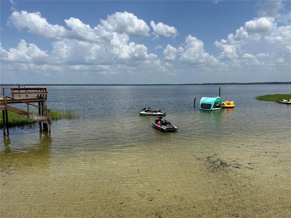 A wooden dock extends into a lake with two jet skis and a floating cabana — 21116 NE 101ST AVENUE UNIT 10, EARLETON, FL