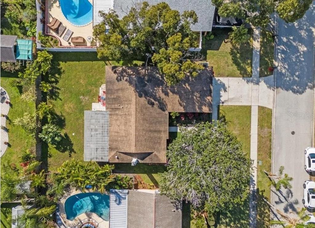An aerial view shows a house with a brown roof, a pool, and surrounding trees — 11145 BELLA LOMA DRIVE, LARGO, FL