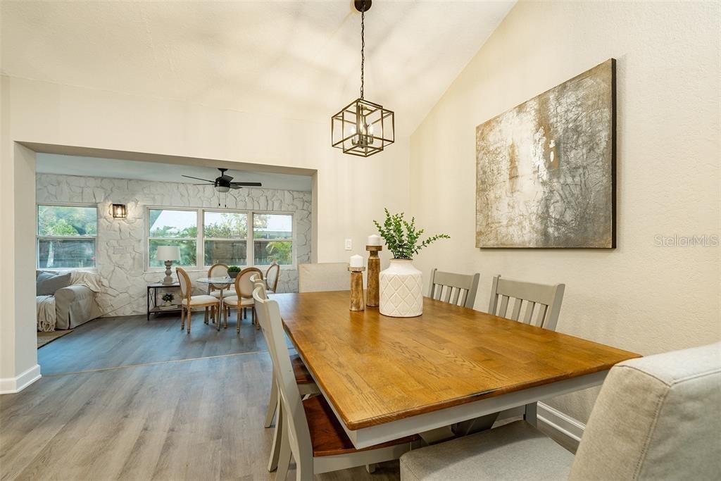A dining room features a wooden table, gray chairs, and a large abstract wall painting — 11145 BELLA LOMA DRIVE, LARGO, FL