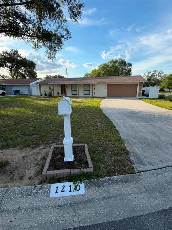 A single-story house with a tan exterior, a two-car garage, and a white mailbox — 1210 BRANDA VISTA DRIVE, BRANDON, FL