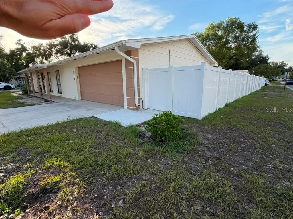 A single-story house with a tan garage door and a white vinyl privacy fence — 1210 BRANDA VISTA DRIVE, BRANDON, FL