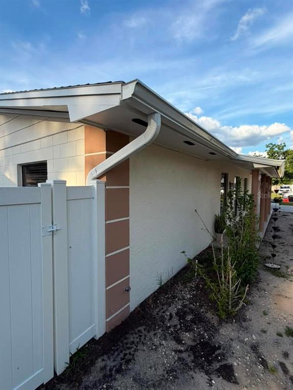 A side view of a house exterior featuring a white fence, gutters, and stucco walls — 1210 BRANDA VISTA DRIVE, BRANDON, FL