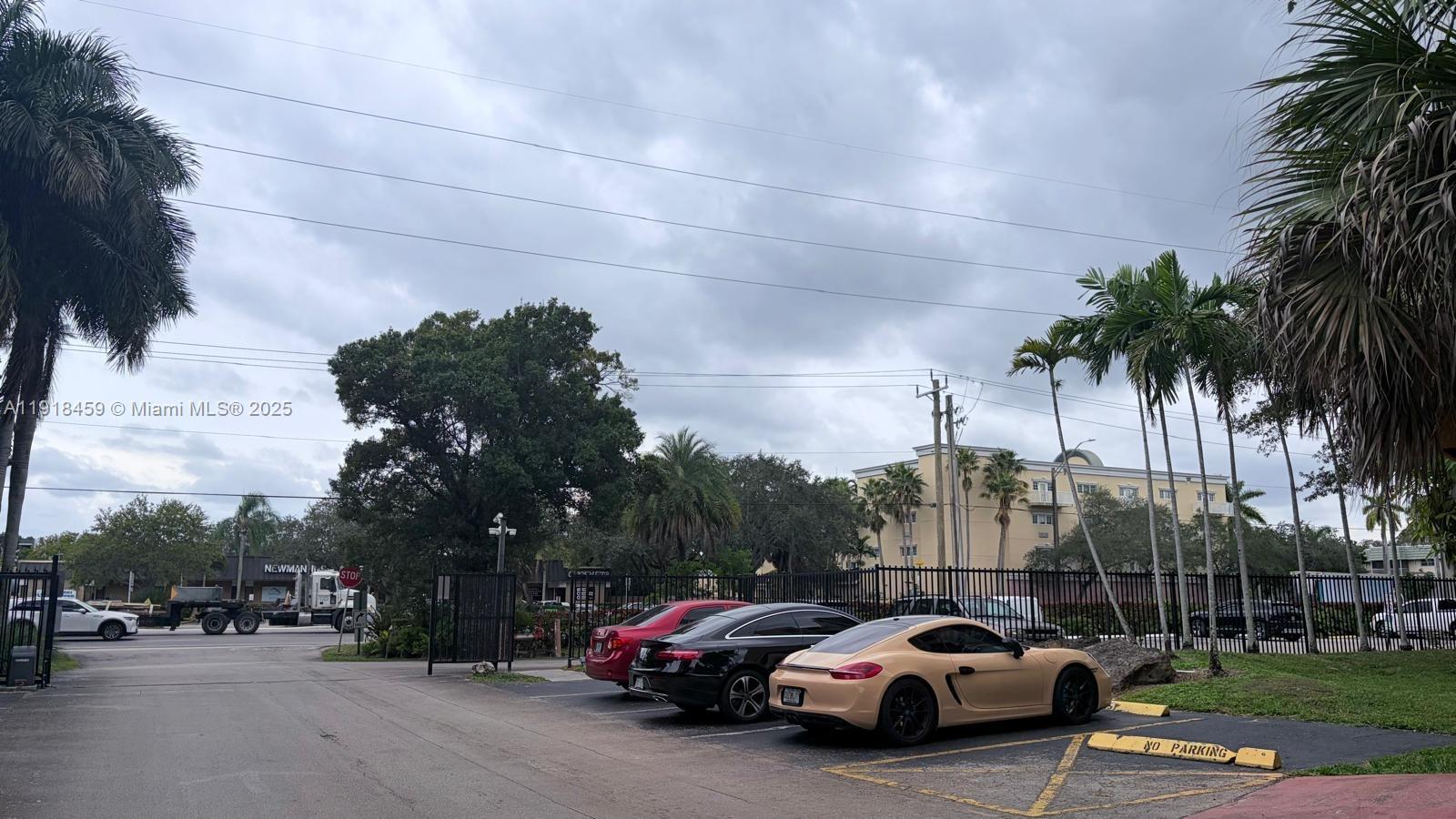 A parking lot features three parked cars in front of a black metal fence — 4111 Stirling Rd # 102, Dania Beach FL 33314, DANIA BEACH, FL