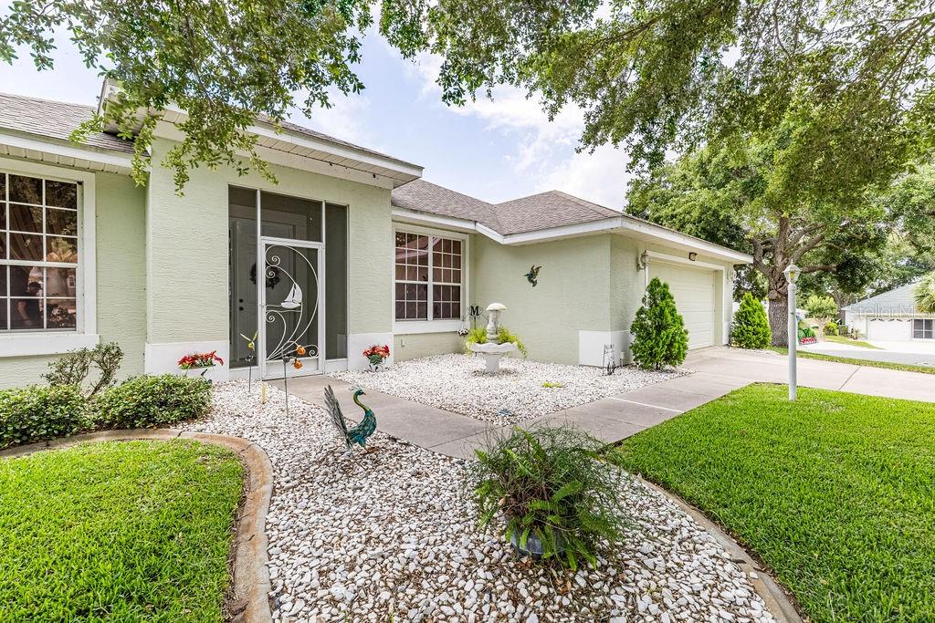 A light green house with a white-trimmed front door, rock landscaping, and a concrete driveway — 3370 SAINT LUCIA COURT, TAVARES, FL