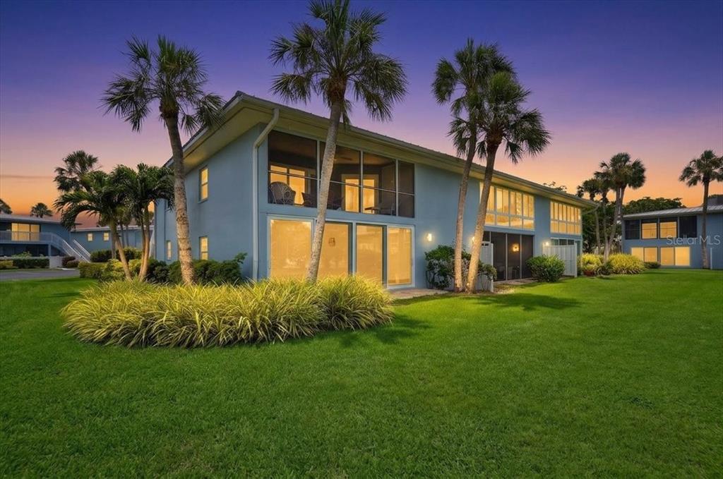 A two-story blue building with screened balconies and palm trees on a grassy lawn — 600 MANATEE AVENUE UNIT 230, HOLMES BEACH, FL