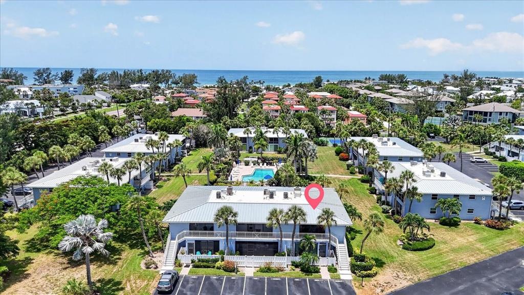 An aerial view shows a multi-story blue residential building with a pool and parking lot — 600 MANATEE AVENUE UNIT 230, HOLMES BEACH, FL