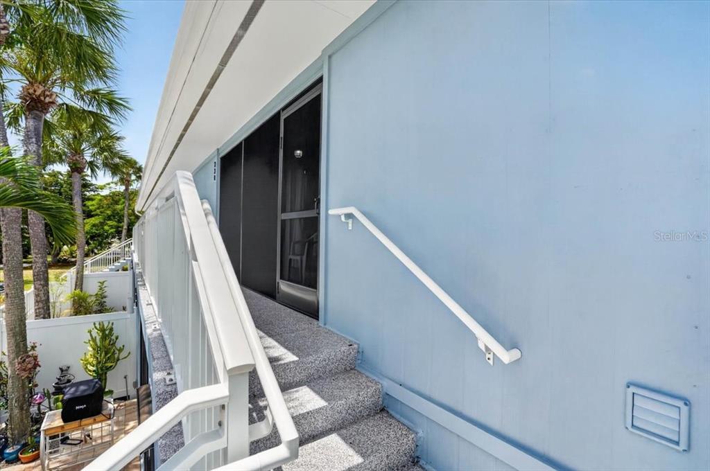 An exterior view shows a blue building with a staircase leading to a screened door — 600 MANATEE AVENUE UNIT 230, HOLMES BEACH, FL