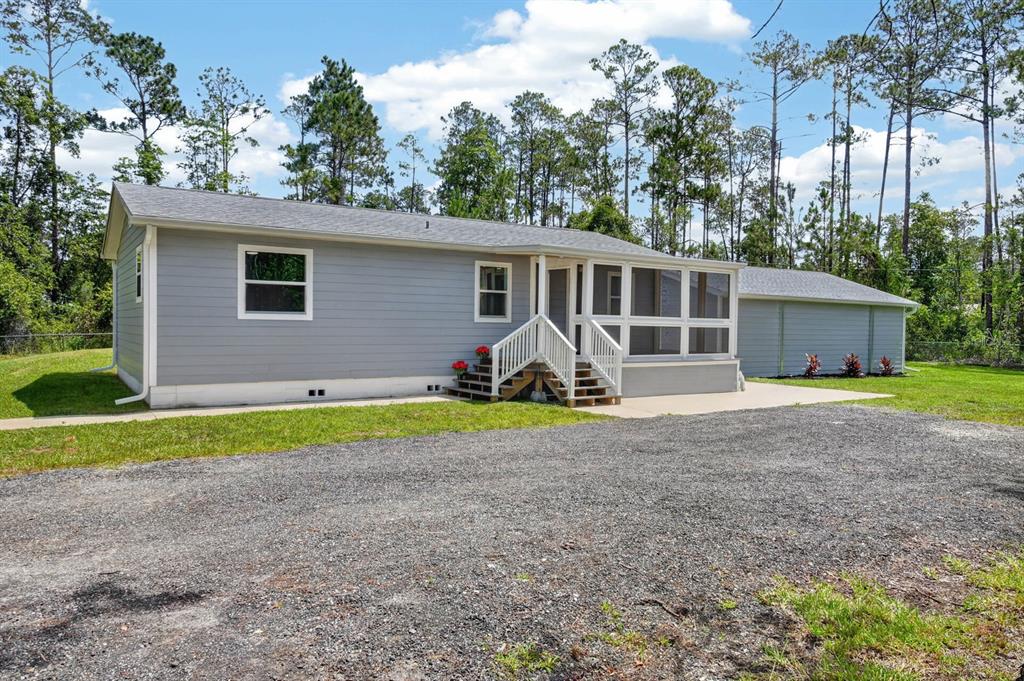 A gray single-story house with a screened-in porch and a gravel driveway — 3798 BREEZY COURT, ORMOND BEACH, FL