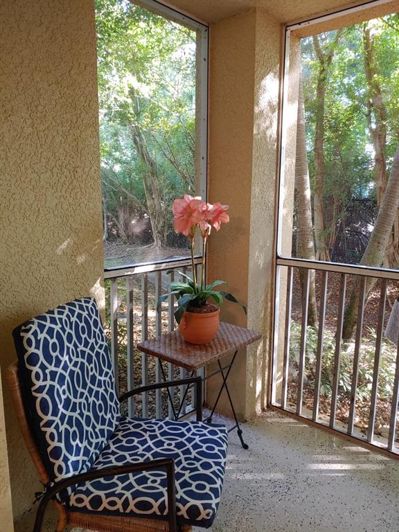 A screened-in porch features a patterned chair, a small side table, and a potted flower — 4122 RESIDENCE DR UNIT 102, FORT MYERS, FL